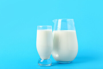 Jug and glass with milk on blue background