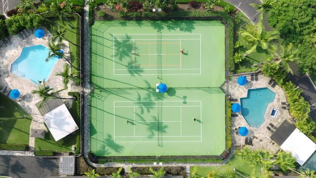 4K drone camera above tennis court with active game match. High quality footage background of tennis court in tropical lavish green garden of resort hotel area at sunset time, Hawaii USA Generative AI