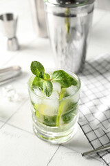 Glass of tasty mojito on light tile background