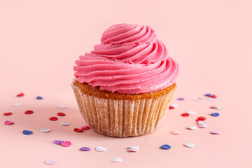 Tasty cupcake and confetti on pink background