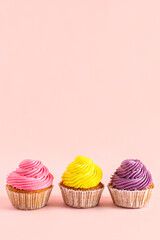 Tasty colorful cupcakes on pink background