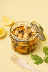 Jar with pickled mussels on beige background