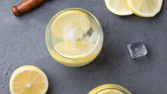 Brazilian sicilian lemon caipirinha in glasses with ice and fruit slices over stone background