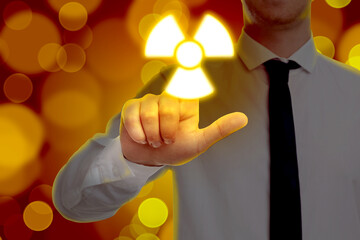Man touching glowing radiation warning symbol on digital screen against red background with blurred...