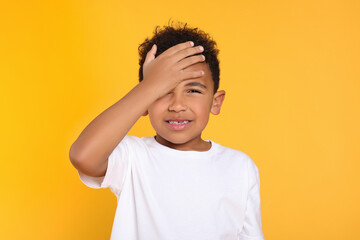 Portrait of emotional African-American boy on yellow background