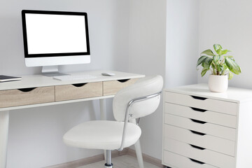Stylish office interior with comfortable chair, desk and computer