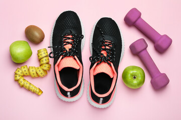 Weight loss concept. Flat lay composition with sneakers, fitness items and fruits on pink background