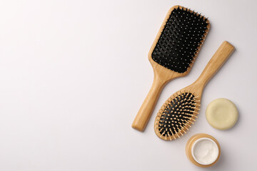 Wooden hairbrushes and cosmetic products on white background, flat lay. Space for text