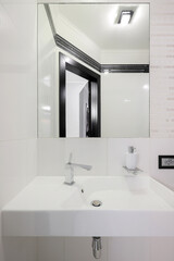 Faucet with ceramic sink and mirror in the bathroom