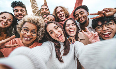 International group of young people laughing at camera outside - Happy friends taking selfie pic with smartphone device - Life style concept with guys and girls hanging out together - obrazy, fototapety, plakaty