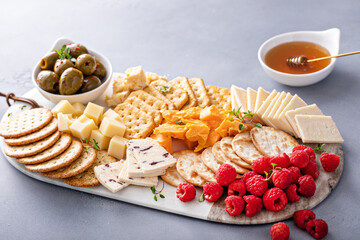 Cheese board or snack board with crackers, cheese, olives and berries