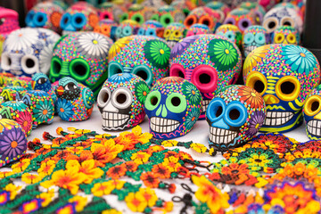 Fototapeta na wymiar Colorful skulls, Mexican handicrafts. Day of the Dead, handmade Huichol figure made of chaquira, Mexico.