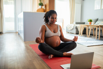 Young pregnant latina woman meditating at home wihle using a laptop
