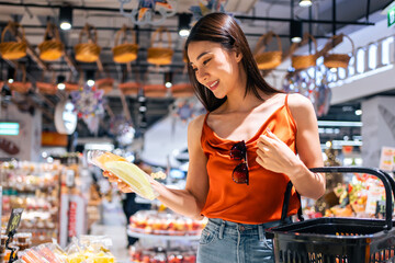 Asian young beautiful woman holding grocery basket walk in supermarket. 