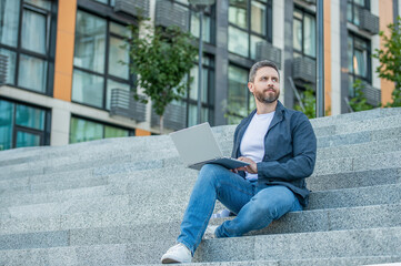 freelancer man with pc outside on stairs. photo of freelancer man with computer.