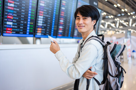 Portrait of Asian young man checking depature boarding pass in airport. 