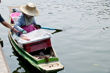Obraz premium BANGKOK, THAILAND - MAY 11, 2023 : Asian female trader rowing boats to sell wooden meatballs along the canal walkway in Thailand.