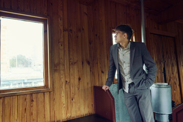young man in a vintage railway car is standing at the seat looking out the window