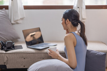 Beautiful Young Asian woman using laptop computer on sofa at home, shopping online with internet in happy mood and Relax part time concept
