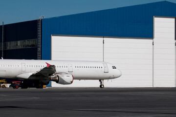 White passenger aircraft near the aviation hangar