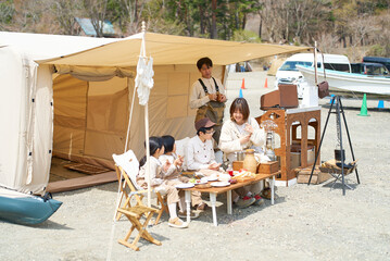 キャンプサイトにテントを立ててくつろぐ家族