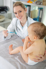 female paediatrician with baby holding a thermometer