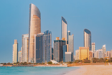 Fototapeta na wymiar Stunning sandy beach near Corniche seaside embankment with great sunset view of Abu Dhabi, UAE towering skyscrapers