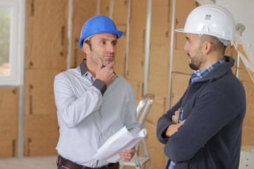 male architects with blueprint working at construction site