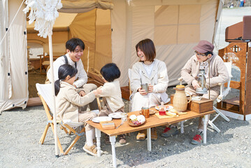 キャンプサイトにテントを立ててくつろぐ家族