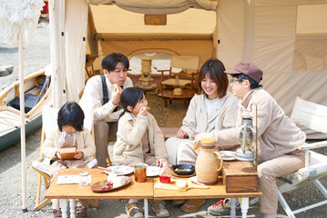 キャンプサイトにテントを立ててくつろぐ家族