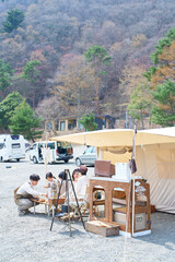 キャンプサイトにテントを立ててくつろぐ家族