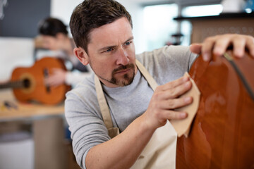 a craftsman sanding a guitar