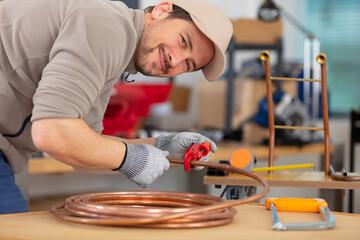 plumber cutting a copper pipe with a pipe cutter