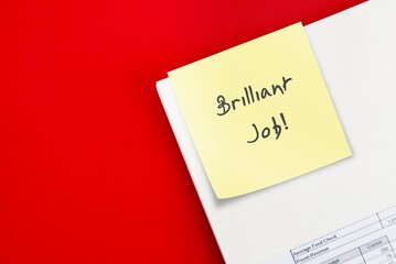 note on document from boss manager supervisor written Brilliant Job on red copy space background,...