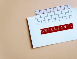 Card stick on beige background with handwritten BRILLIANT!, concept of compliment or praise giving...