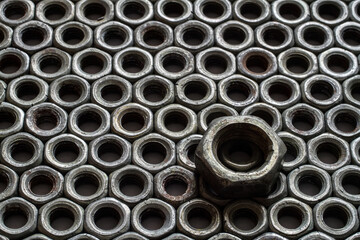 Iron nuts. One big nut against a background of small nuts. Steel fasteners.