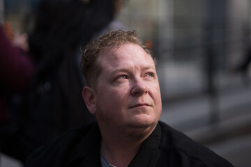 A disabled transman rides his powerchair in the city. His intimate portrait is accentuated by dramatic afternoon light to express strength, and the humanity of accessibility and gender rights.