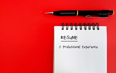 Pen ,crumpled paper and a notebook with resume head title - all on red background with copy space....