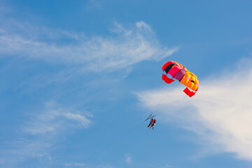 Parachutists fly in the blue sky with a colorful parachute