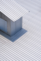 Sunlight on surface of small room on corrugated metal roof in vertical frame, street minimal architecture background