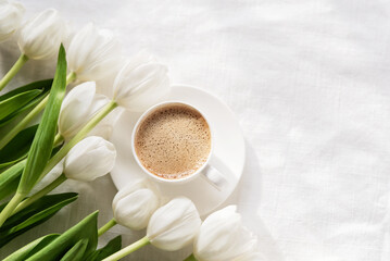 Obraz na płótnie Canvas Cozy morning coffee cup with white tulip flowers from above, breakfast on Mothers day or Womens day. Top view with copy space Floral composition Romantic background