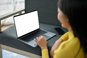 Close up view of young beautiful Asian woman using blank screen laptop on her sofa