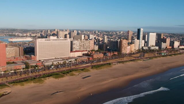 High drone aerial of Durban beachfront and city skyline in the early morning sun. Harbor is in the distant background.