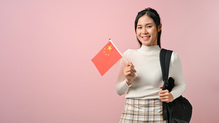 Asian girl showing a China flag on pink isolated background, education concept.