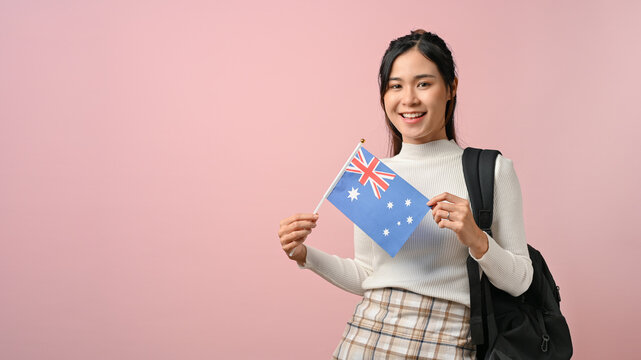 Beautiful girl showing a Australia flag on pink isolated background, education concept.