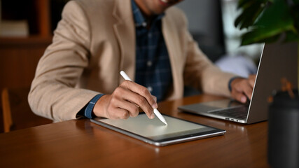 Close-up image of a professional adult Asian businessman using his laptop and tablet
