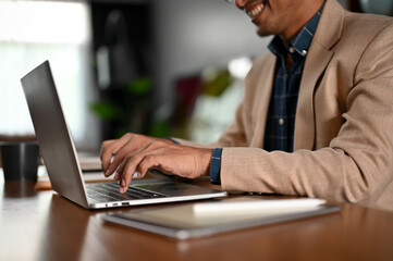 A professional and smart adult Asian businessman using his laptop computer at her desk.