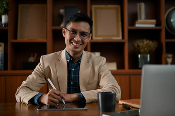 Portrait of a successful mature Asian businessman in formal business suit sits at her desk