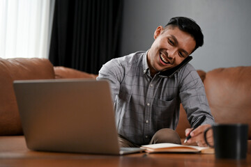 Busy and professional mature Asian businessman working from home, talking on the phone