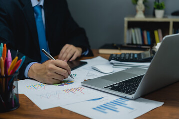 Fototapeta na wymiar Business man holding pen with analysis financial graph and report marketing statistic chart on desk.